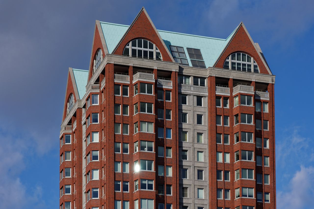 A striking view of a modern residential tower against a blue sky in Rotterdam.
