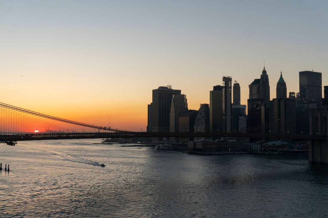 Stunning view of Brooklyn Bridge and Manhattan skyline captured during sunset over the New York City waterfront.