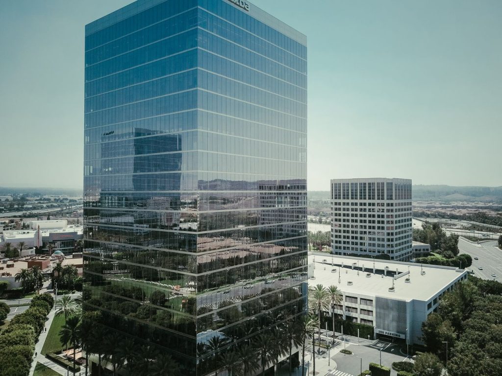 Tall glass skyscraper reflecting the cityscape in a modern urban setting under a clear sky.